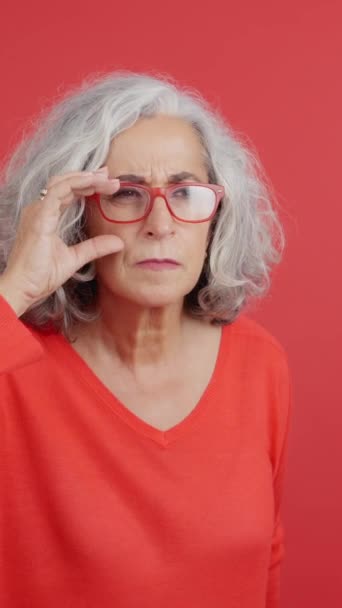 Студійний Портрет Червоним Тлом Зрілої Жінки Піднімає Окуляри Щоб Побачити — стокове відео