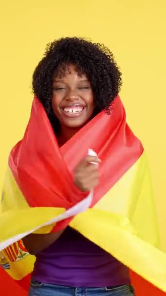 Μεταναστευτική Γυναίκα Αφρο Μαλλιά Τυλιγμένη Ισπανική Σημαία Στούντιο Κίτρινο Φόντο — Αρχείο Βίντεο