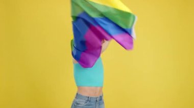Stüdyoda sarı arka planda lgbt gökkuşağı bayrağı sallayan mutlu bir gay.