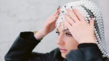 Bir kadının inci bir peruk takarken aynaya baktığı yavaş çekim videosu.