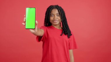 Stüdyodaki kırmızı arka planı olan Afrikalı kadının cep telefonunun boş ekranı.