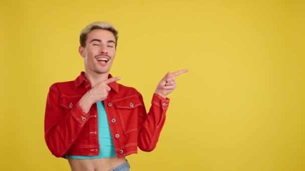 Lächelnder Schwuler Mann Zeigt Studio Mit Gelbem Hintergrund Eine Leerstelle — Stockvideo