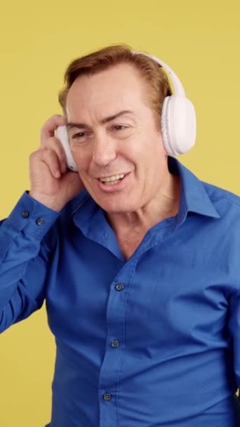 Smiley Mature Man Listening Music Mobile Headphones Studio Yellow Background — Stock Video