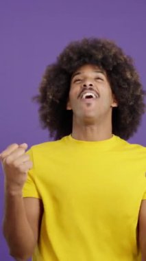 Happy african man looking at the camera and celebrating raising the fists in studio