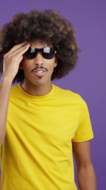 Happy african man with sunglasses standing with arms crossed and smiling at the camera in studio