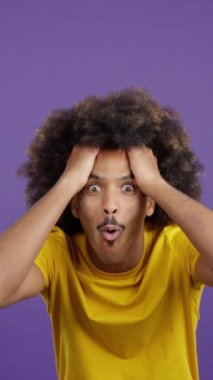 Cool surprised african man with curly hair looking at the camera gesturing in studio