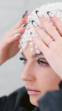 Bir kadının inci bir peruk takarken aynaya baktığı yavaş çekim videosu.