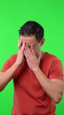 Kırmızı gömlekli, başı ağrıyan bir adam. Orta boy. Krom yeşil arkaplan.