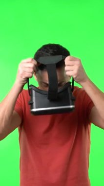 Modern VR gözlüklerinde ağzı açık, sanal gerçekliği keşfeden ve kromakey üzerinde tek başına duran hayret verici erkek oyuncu.