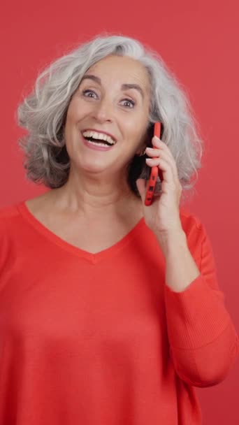 Studio Video Red Background Surprised Mature Woman Talking Mobile — Vídeo de Stock