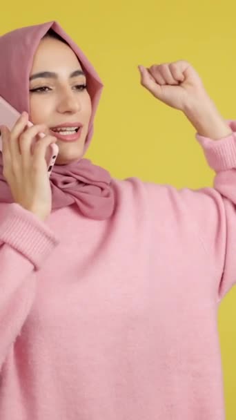 Happy Muslim Woman Celebrating While Talking Mobile Phone Studio Yellow — Vídeos de Stock