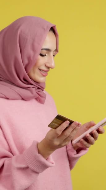 Мусульманка Использующая Мобильный Телефон Карточку Покупок Онлайн Студии Желтым Фоном — стоковое видео