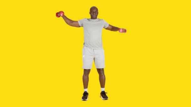 Видео Студии Жёлтым Фоном Африканца Делающего Изометрические Боковые Упражнения Поднятию — стоковое видео
