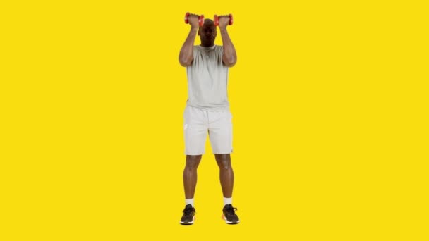 Wideo Studio Żółtym Tłem Afrykanina Wykonującego Pionowe Ćwiczenia Skurczowe Hantlami — Wideo stockowe