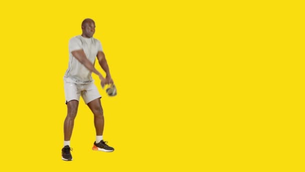 Wideo Studio Żółtym Tłem Silnego Afrykanina Robi Swing Exercise Kettlebell — Wideo stockowe