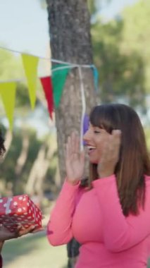 Multiethnic friends clapping and singing Happy Birthday in a park