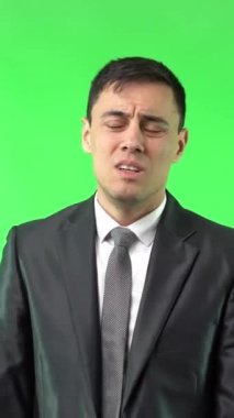 Siyah takım elbiseli, sıkı sıkı sarılmış ellerle yalvaran ve krom tuşa karşı kameraya bakan ciddi bir yetişkin erkek.