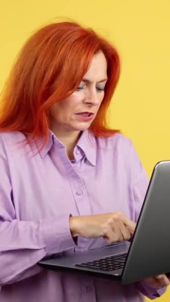 Зріла Руда Жінка Має Проблеми Ноутбуком Студії Жовтим Тлом — стокове відео