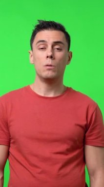 Uykulu bir adam, yarı uykulu, yataktan yeni kalktı, kırmızı bir gömlek giyiyor. Orta boy. Krom yeşil arkaplan.