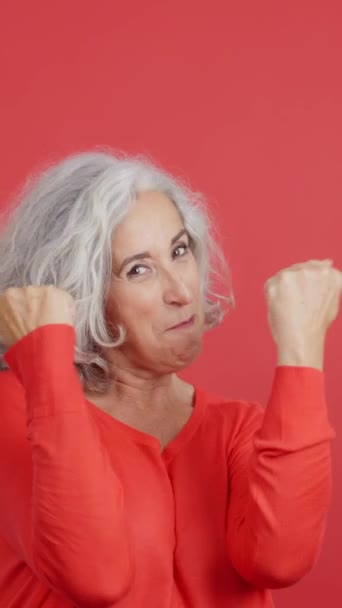 Studio Video Red Background Mature Woman Celebrating While Raising Fists — Stockvideo