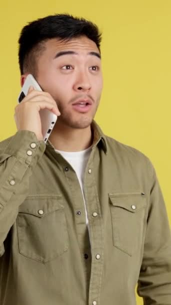 Zaskoczony Chińczyk Otwierający Usta Podczas Rozmowy Telefonem Studio Żółtym Tłem — Wideo stockowe