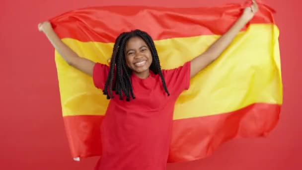 快乐的非洲女人笑着在有红色背景的工作室升起西班牙国旗 — 图库视频影像