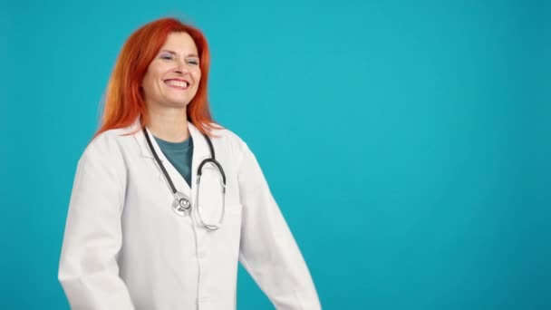 笑成熟的红头发女医生看着复印空间 蓝色背景 — 图库视频影像
