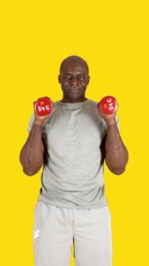 Stüdyoda çekiç kıvıran Afrikalı bir adamın sarı arkaplanlı videosu var.