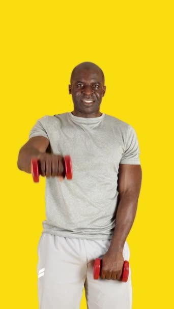 一个有着黄色背景的非洲男人用哑铃交替做正面隆起练习的视频 — 图库视频影像