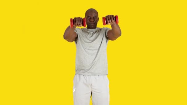 Stüdyoda Afrikalı Bir Adamın Sarı Arkaplanlı Videosu Var Dambıllarla Yükseltme — Stok video