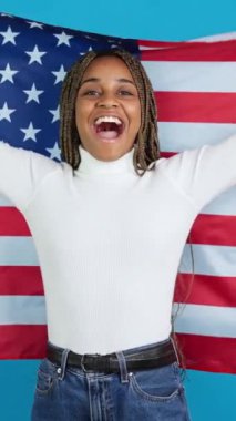 Kuzey Amerika bayrağını göndere çeken gururlu bir Afrikalı kadının mavi arka planlı videosu.