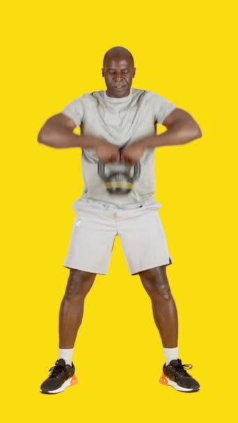 Wideo Studio Żółtym Tłem Silnego Afrykanina Wykonującego Ćwiczenia Wioślarskie Kettlebell — Wideo stockowe