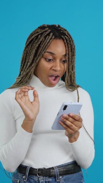 Video Blue Background African Woman Looking Mobile Phone Expression Surprise — Vídeo de Stock