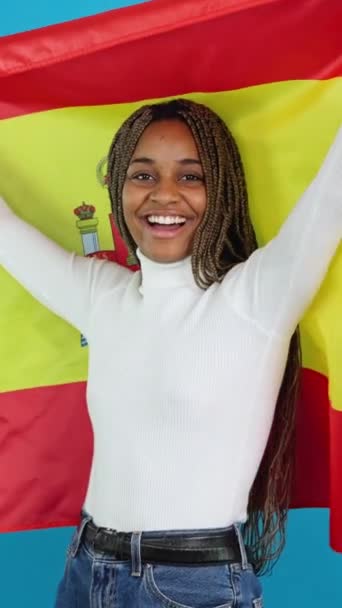 Mutlu Bir Afrikalı Kadının Spanyol Bayrağı Çekerken Çekilmiş Mavi Arkaplan — Stok video
