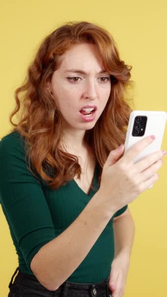 Mulher Ruiva Preocupada Usando Telefone Celular Estúdio Com Fundo Amarelo — Vídeo de Stock