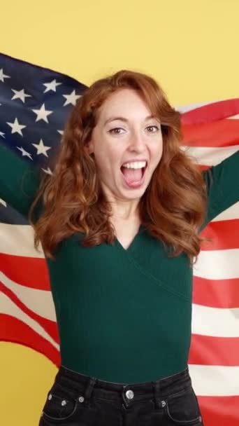 Счастливая Рыжая Женщина Поднимает Национальный Флаг Северной Америки Студии Жёлтым — стоковое видео