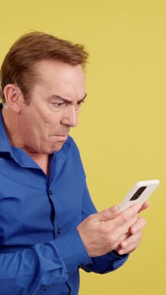 Überraschter Älterer Mann Schaut Studio Auf Das Handy Mit Gelbem — Stockvideo