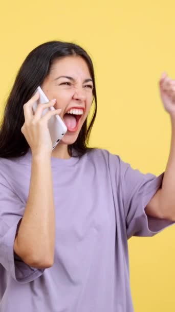 Щаслива Жінка Святкує Беручи Мобільний Телефон Студії Жовтим Фоном — стокове відео