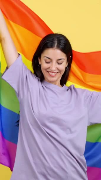 快乐的高加索女人在有黄色背景的演播室里升起了一磅彩虹旗 — 图库视频影像