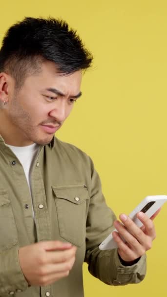 Chinese Man Gesturing Worried While Using Mobile Studio Yellow Background — Stock Video