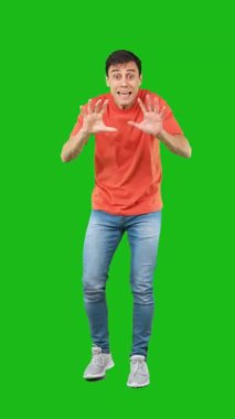 Stüdyoda yeşil arka planda izole edilmiş, günlük kıyafetlerle gülümseyen bir erkek vücudu.