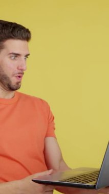 Caucasian man with a surprised look using a laptop in studio with yellow background
