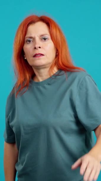 赤毛成熟した女性ジェスチャー禁止とともに手でスタジオで青背景 — ストック動画