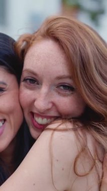 En iyi arkadaşlar sokakta kameraya gülümserken kucaklaşırlar.