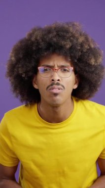African man with curly hair taking off her glasses to see far away in studio