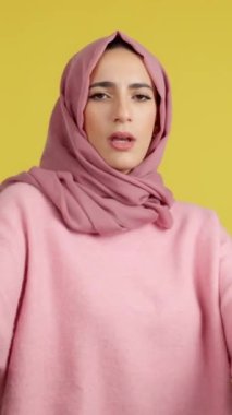 Kaba Müslüman kız, kameraya bakarak boks yapıyor. Sarı arkaplan