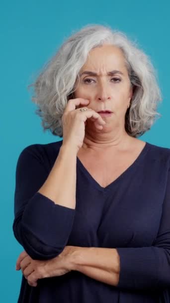 成熟した女性の青い背景を持つスタジオビデオ腕を組んで退屈の表現で検索 — ストック動画