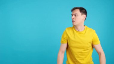 Stüdyoda mavi arka planı olan kızgın bir adam boş alanı işaret ediyor.