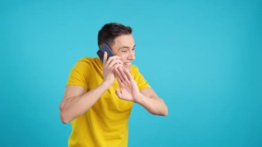 Stüdyoda cep telefonuyla konuşan öfkeli bir adamın mavi arkaplanlı videosu. Çerçeve boş başlar, adam aşağıdan görünür ve altta kaybolur..
