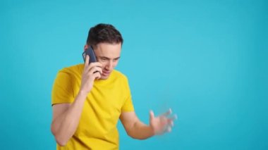 Stüdyoda cep telefonuyla konuşan bir adamın mavi arkaplanlı videosu. Çerçeve boş başlar, adam aşağıdan görünür ve altta kaybolur..
